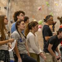 group of 9 competitors watching others on the wall and waiting for their turn